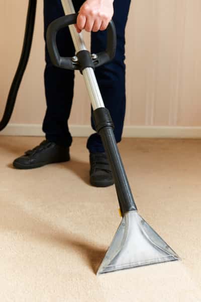 This is a photo of a man steam cleaning a cream carpet, using a professional steam cleaning machine works carried out by Rickmansworth Carpet Cleaning