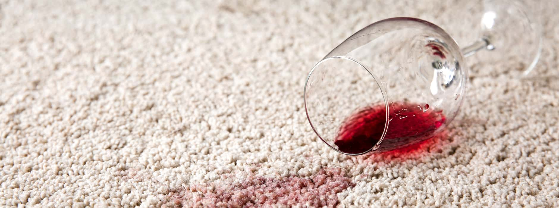 This is a photo of Rickmansworth Carpet Cleaning red wine which has been spilt on a cream carpet. The glass is on its side.