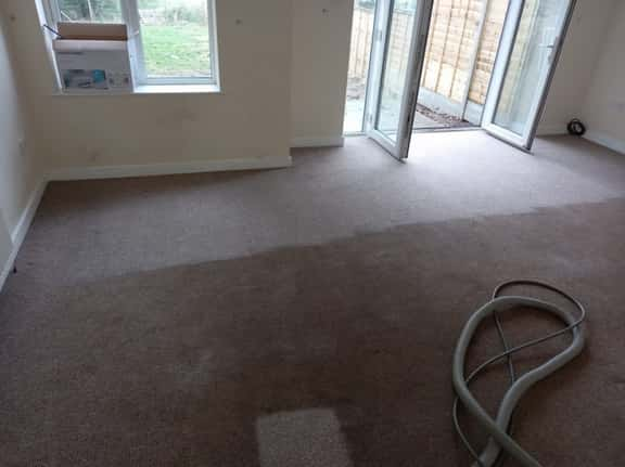 This is a photo of an empty living room with a brown carpet that is in the process of having its carpets steam cleaned works carried out by Rickmansworth Carpet Cleaning